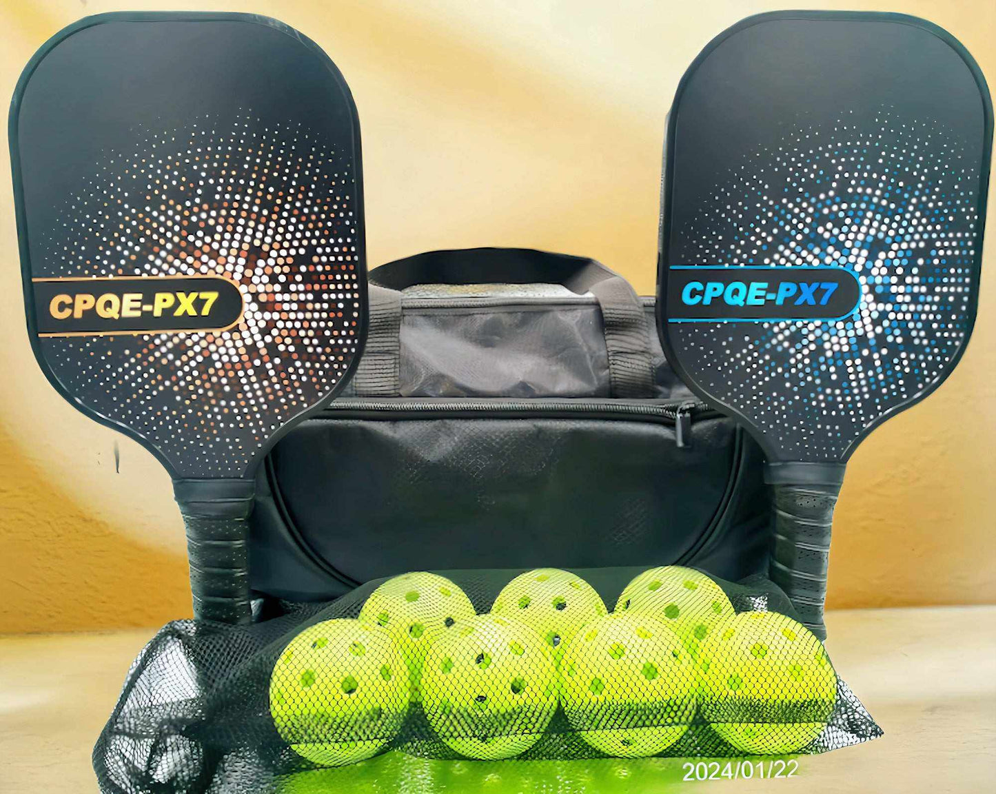 Pickleball bundle with two CPQE fiberglass paddles (gold and blue), seven pickleballs, black mesh ball bag, and black nylon carry bag.